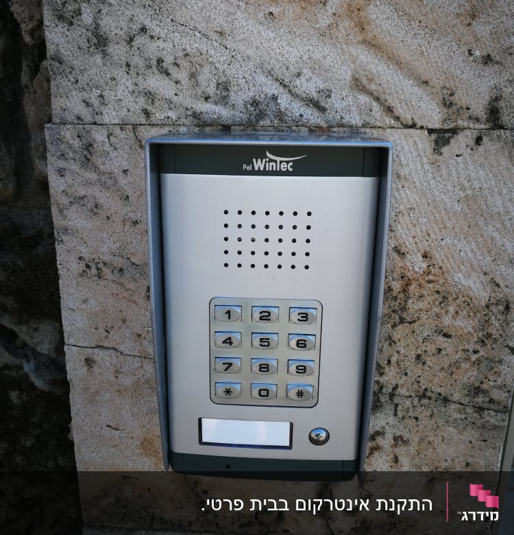 אינטרקום מתכת עם לוח מקשים על קיר אבן